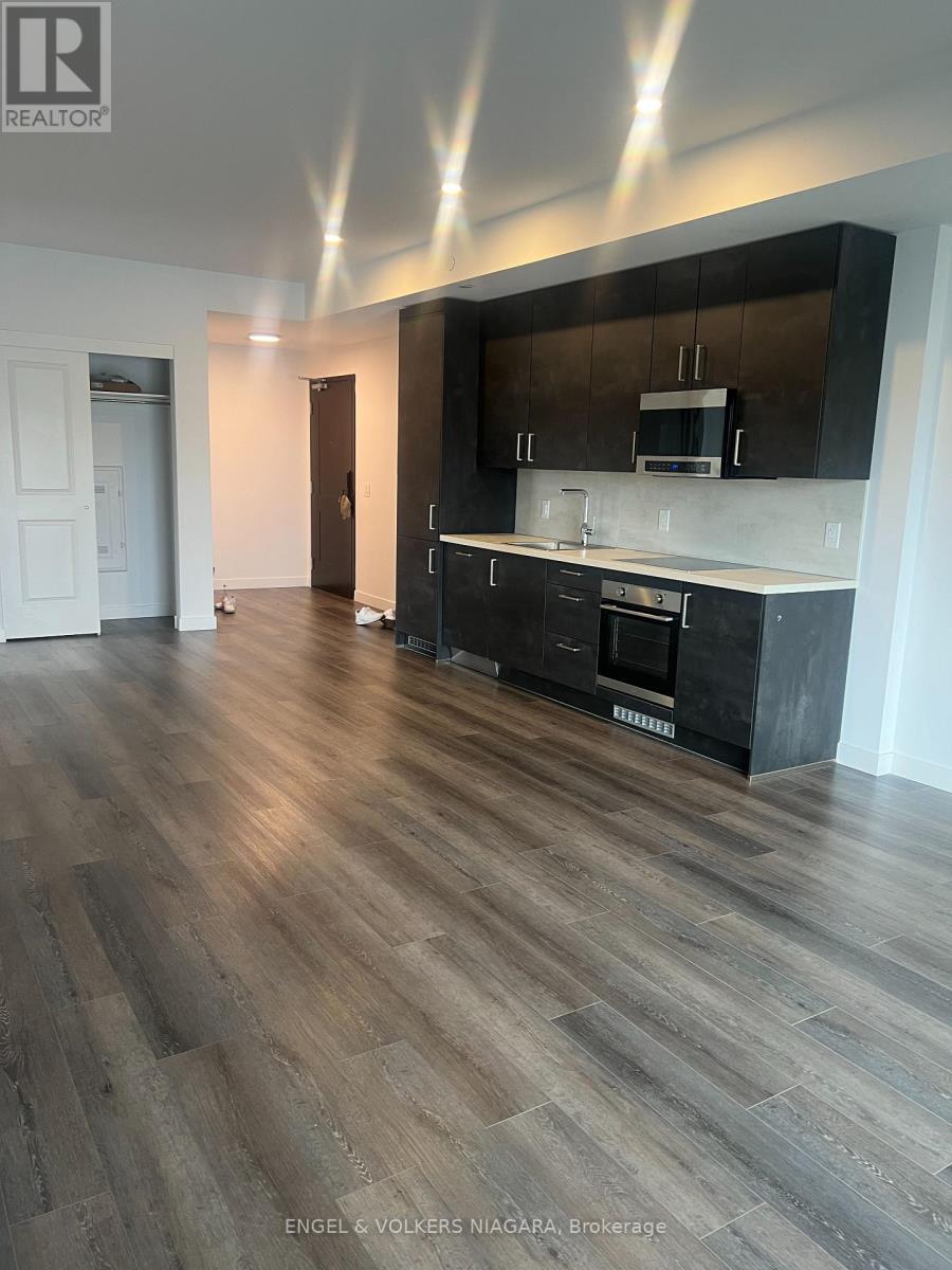 A modern kitchen with wooden floors and black cabinets.
