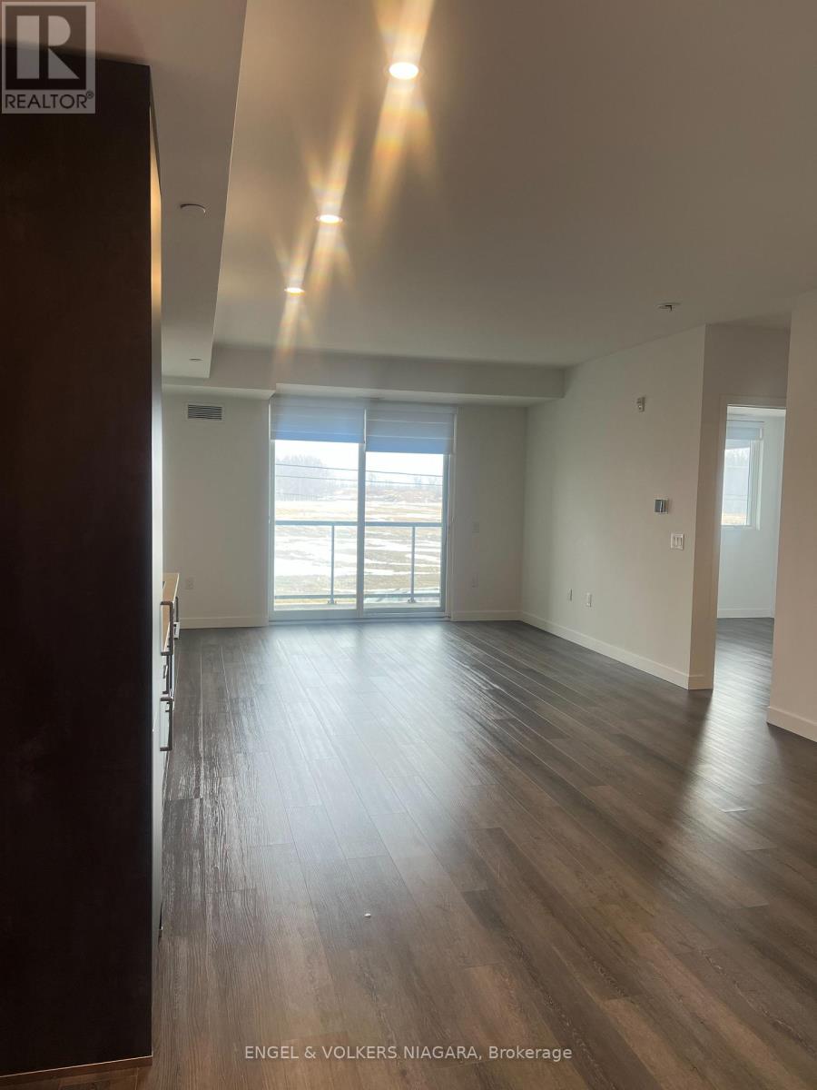 A spacious room with wooden floors and a large window.