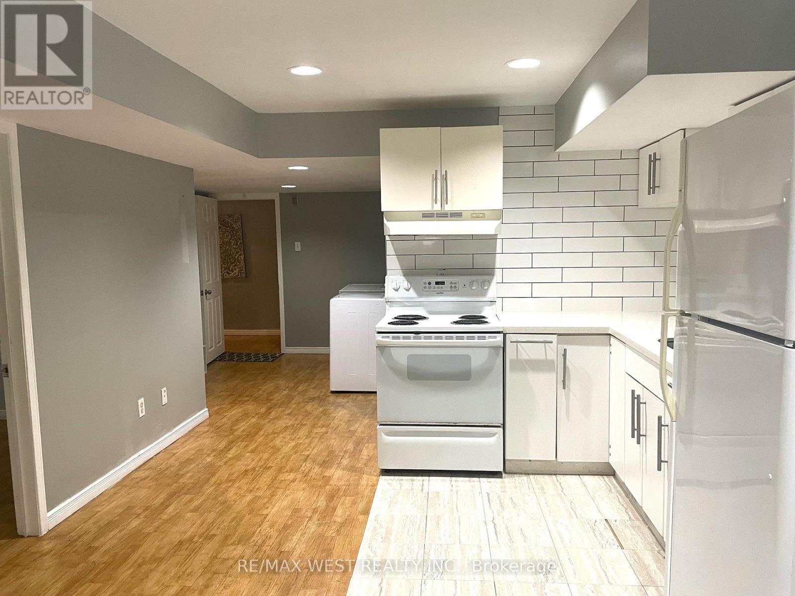 A kitchen with white appliances and wooden floors.