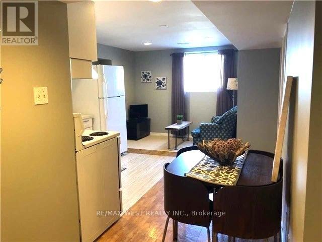 A kitchen with a refrigerator, a dining table with a chair and a sofa in the background.