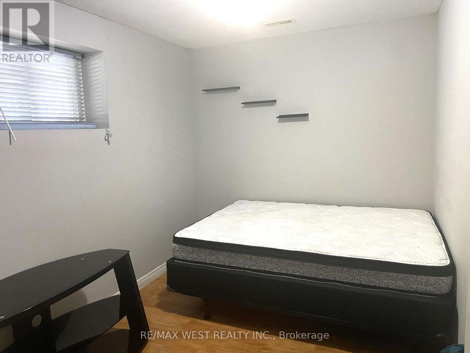 A bedroom with a bed, a table, and a window with blinds.