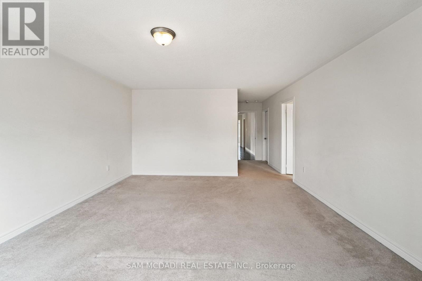 A spacious, empty room with a carpeted floor and white walls.
