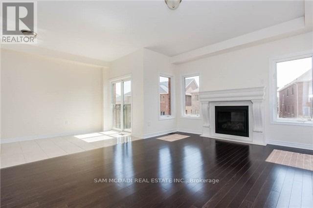 A large, empty room with a fireplace and wood flooring.