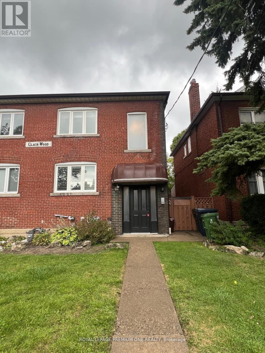 A red brick house with a black door and a sign that says "CLAIMS WOOD".