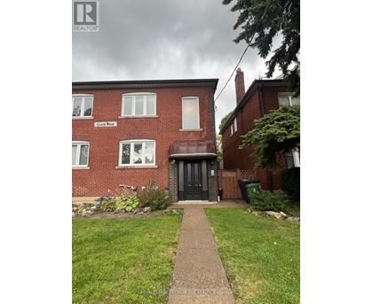 A red brick house with a black door and a sign that says "CLAIMS WOOD".