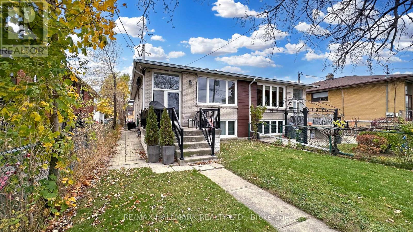 A house with a front yard and a tree with yellow leaves.