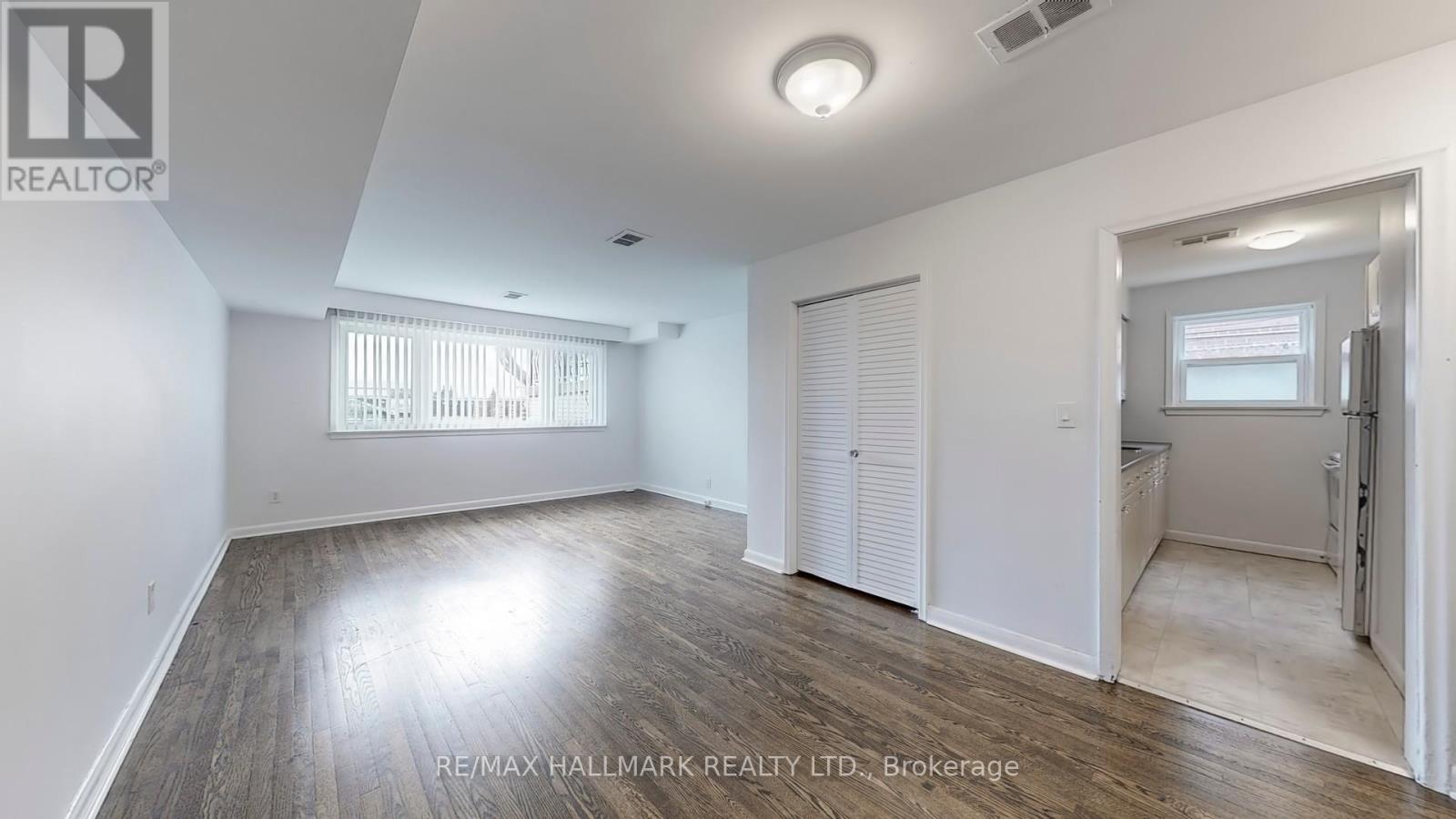 A spacious room with a window and a door leading to another room.