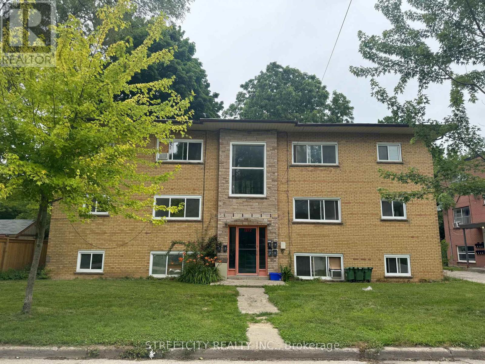 A brick apartment building with a tree in front.