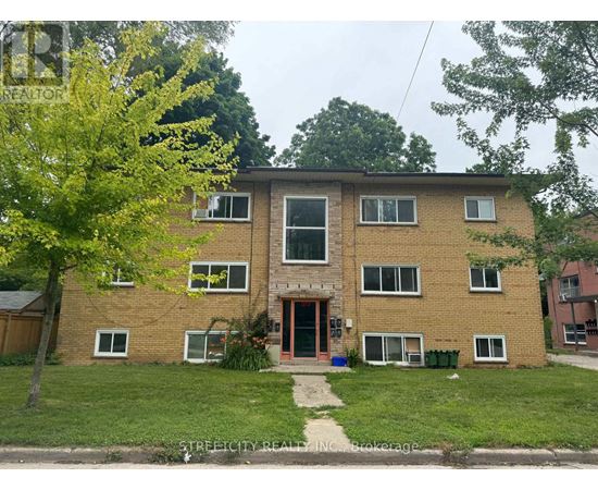 A brick apartment building with a tree in front.