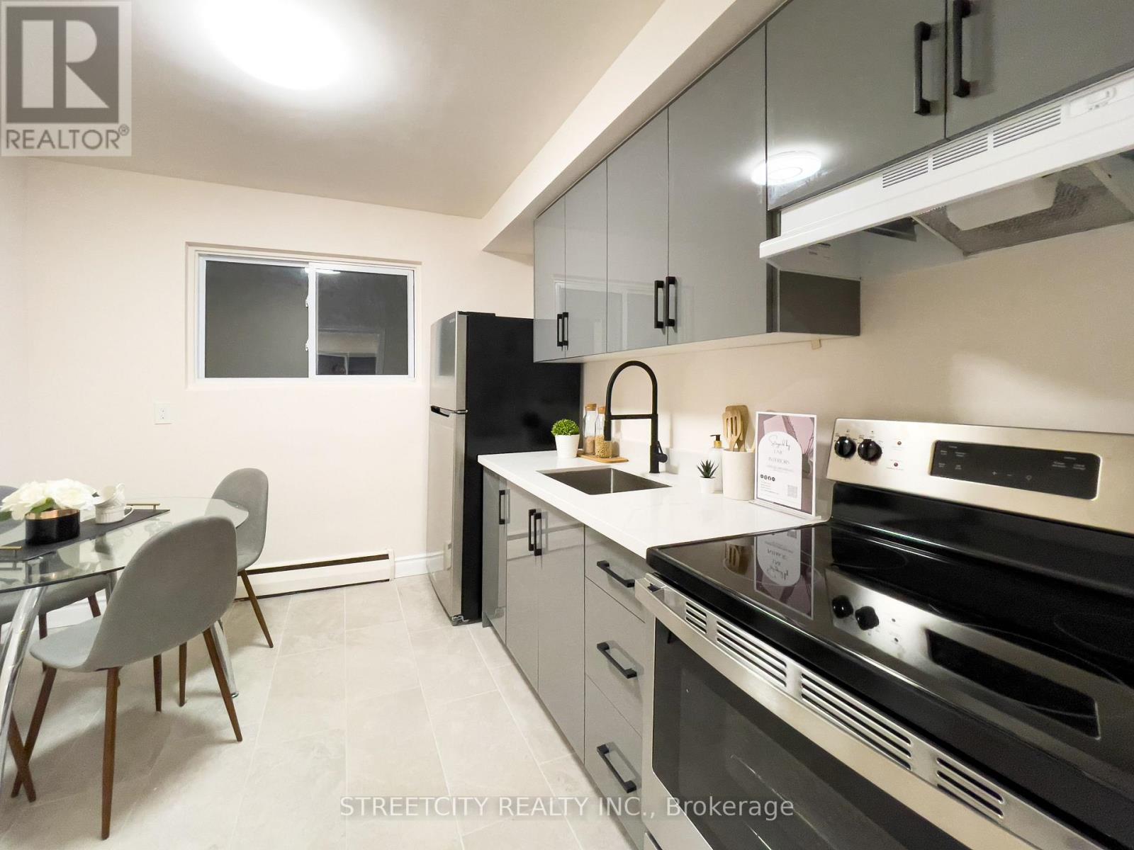 A modern kitchen with a glass table and chairs, a refrigerator, and a stove top oven.