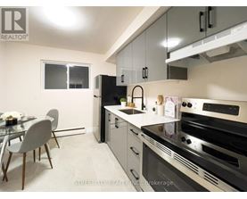 A modern kitchen with a glass table and chairs, a refrigerator, and a stove top oven.