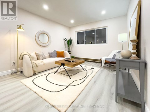 A living room with a white couch, a coffee table, and a rug with a black design on it.