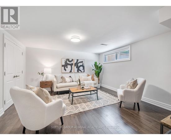 A living room with a white sofa, two white chairs, and a coffee table.