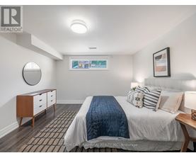 A bedroom with a bed, nightstand, and a round mirror on the wall.