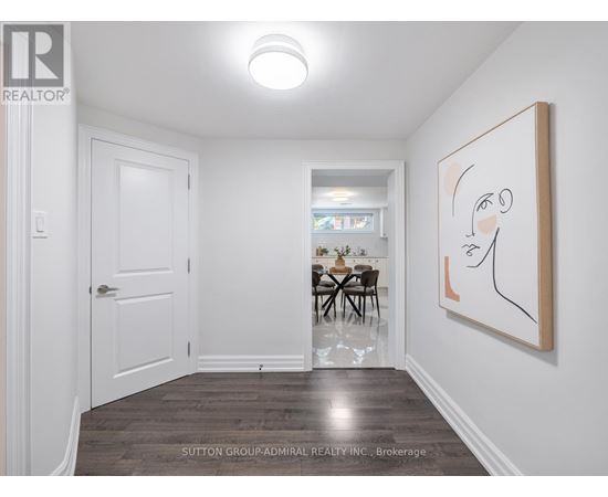 A room with a white door, a dining table with chairs, a painting on the wall, and a wooden floor.