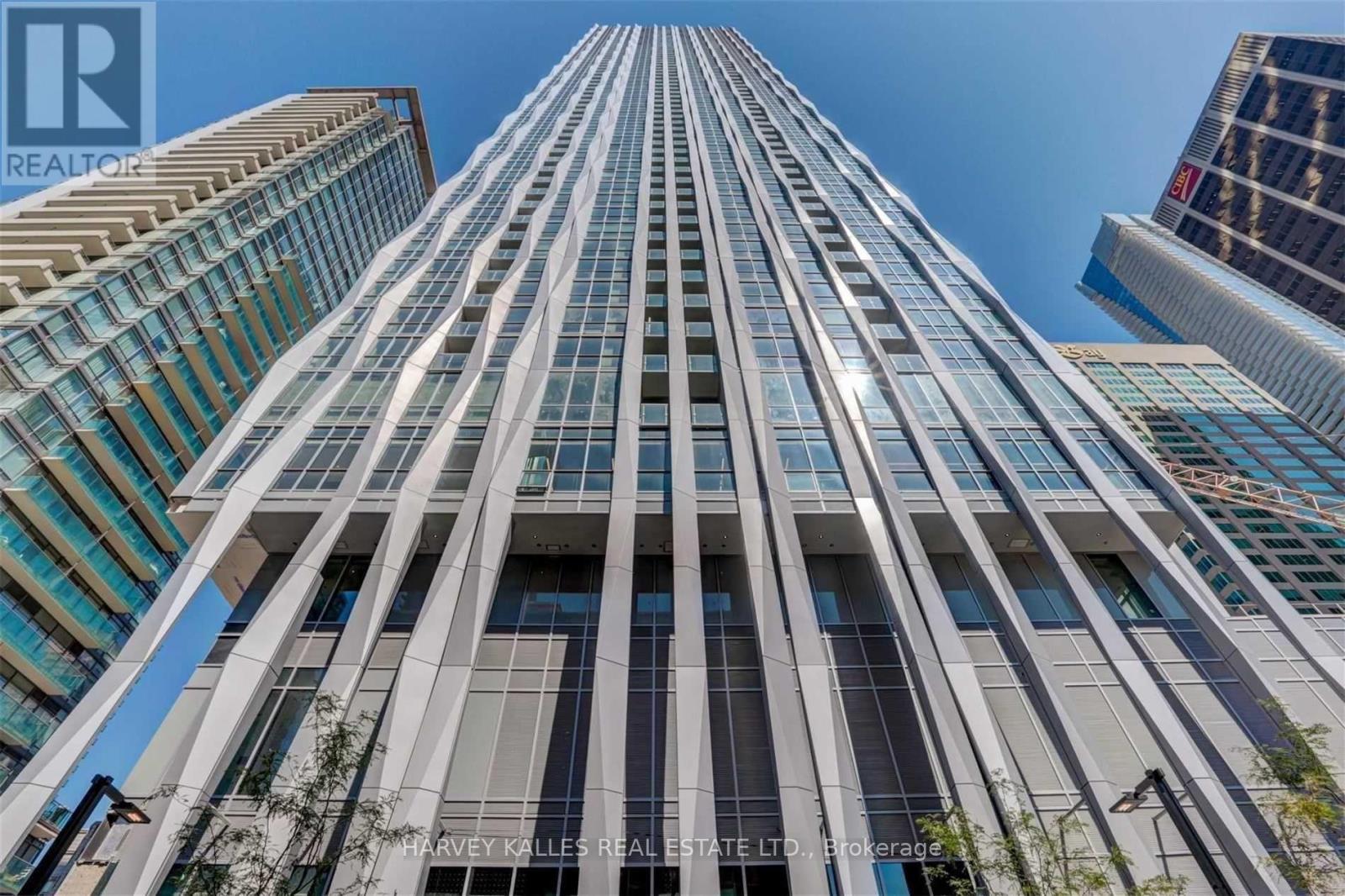 A tall building with a glass facade stands in front of other buildings.