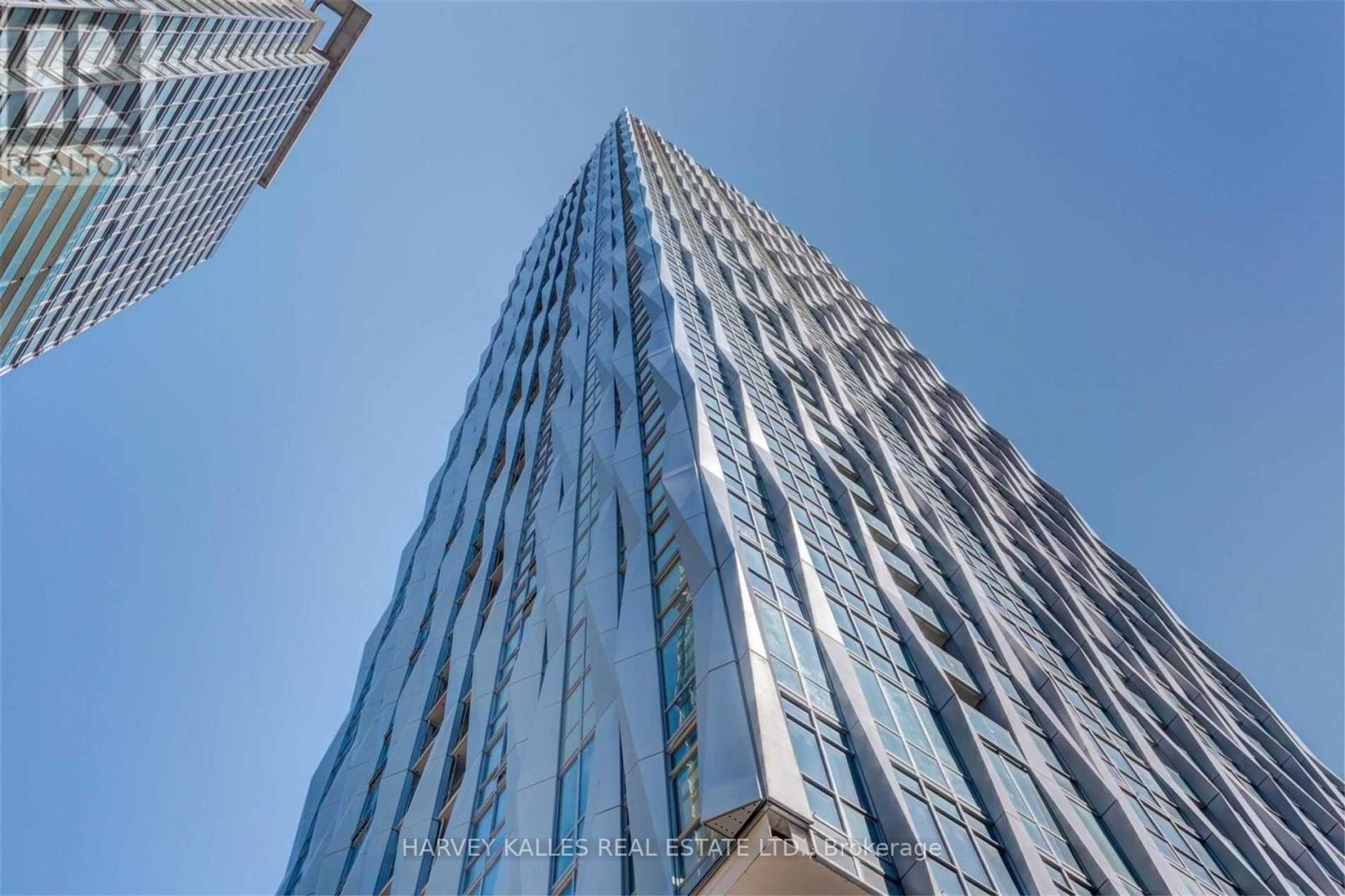 A tall building with a glass facade stands under a clear blue sky.