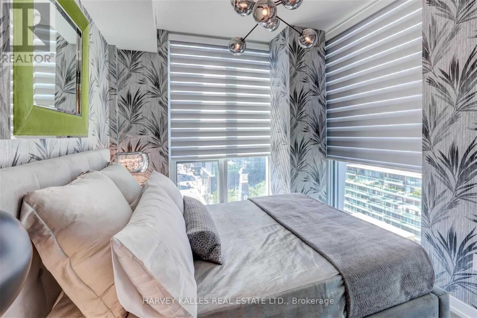 A bedroom with a large bed and a window with blinds.