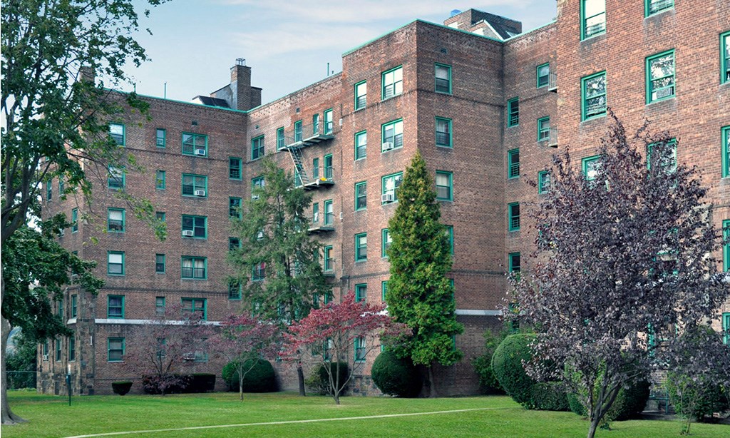 a large brick building with green grass and trees