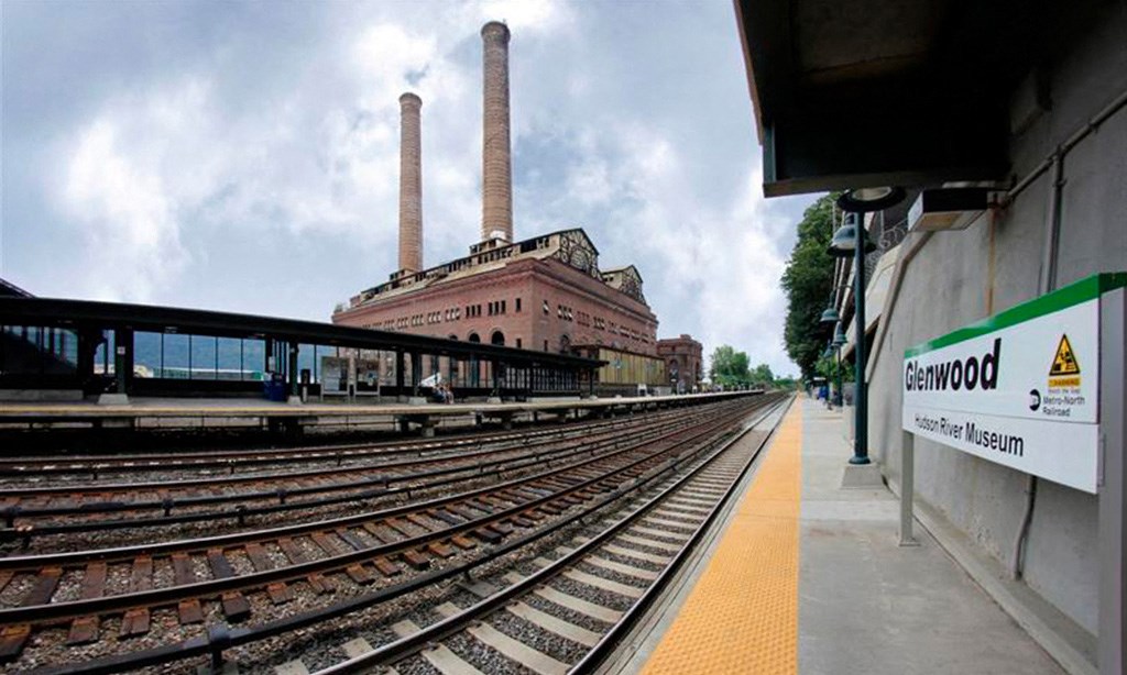 a train station with train tracks and a building with two chimneys