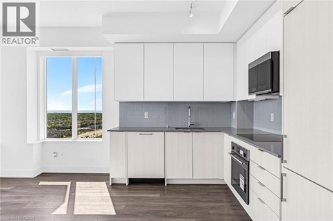A modern kitchen with white cabinets and a black microwave.