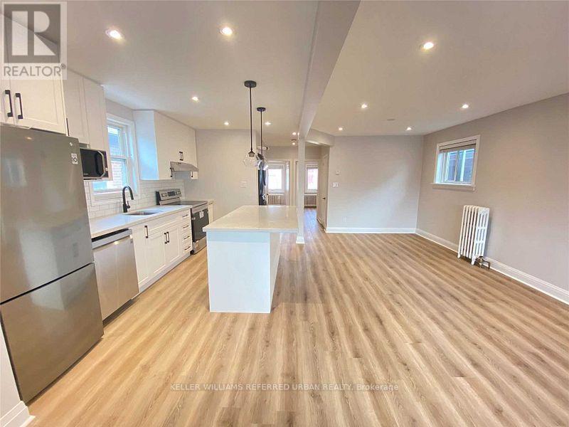 A spacious kitchen with wooden flooring and stainless steel appliances.