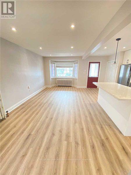 A spacious room with wooden flooring and a large window.