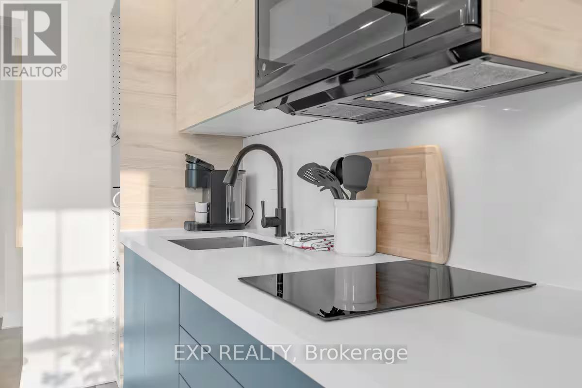 A modern kitchen with a sink, stove, and a microwave mounted above it.