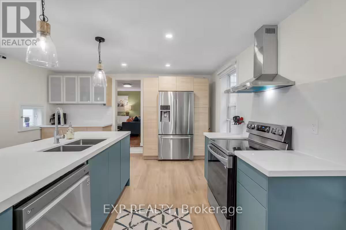 A modern kitchen with a stainless steel refrigerator and a dining area in the background.