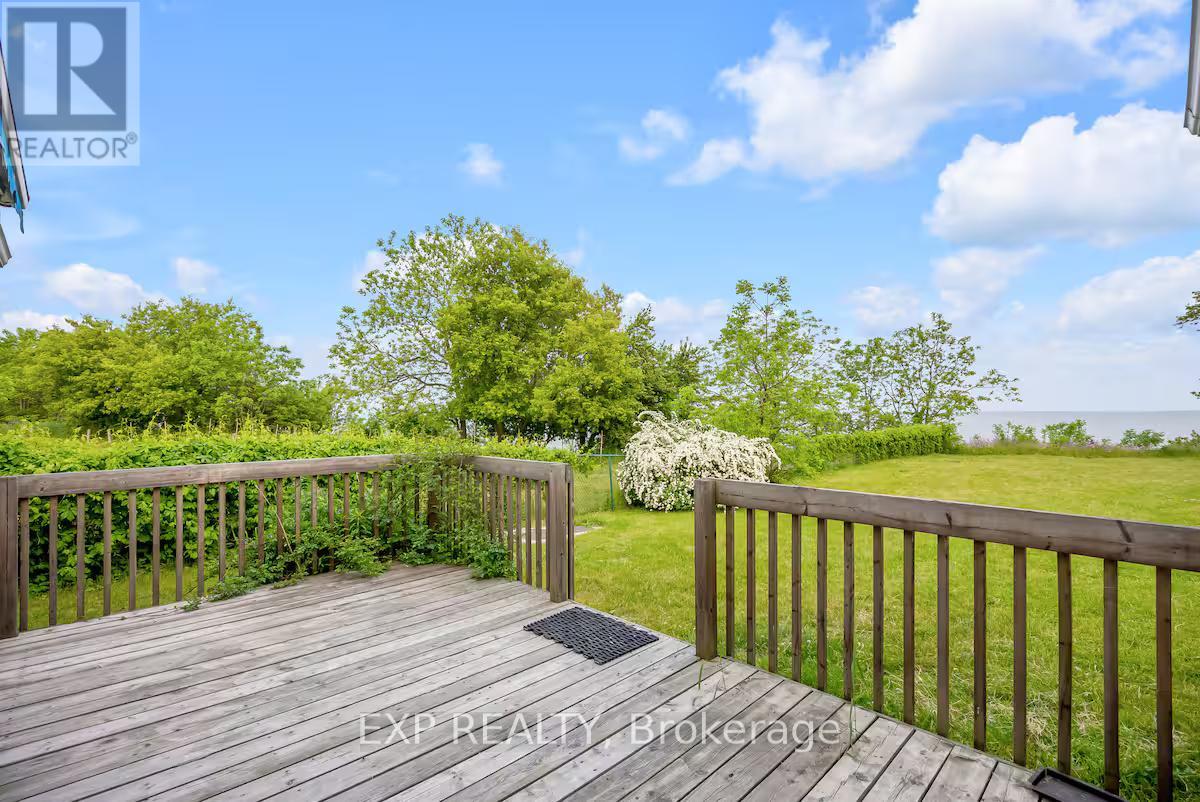 A wooden deck with a railing and a view of a grassy area.