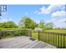 A wooden deck with a railing and a view of a grassy area.