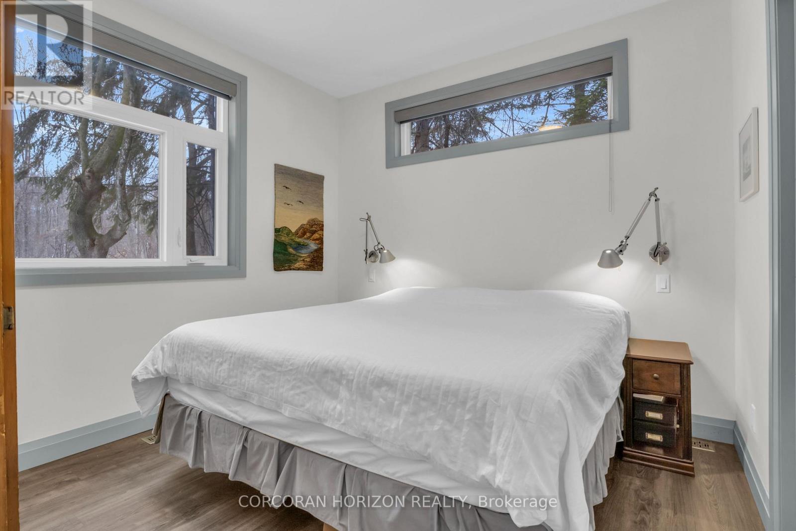 A bedroom with a large bed and a window with a view of trees.