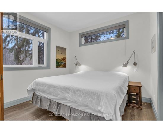 A bedroom with a large bed and a window with a view of trees.
