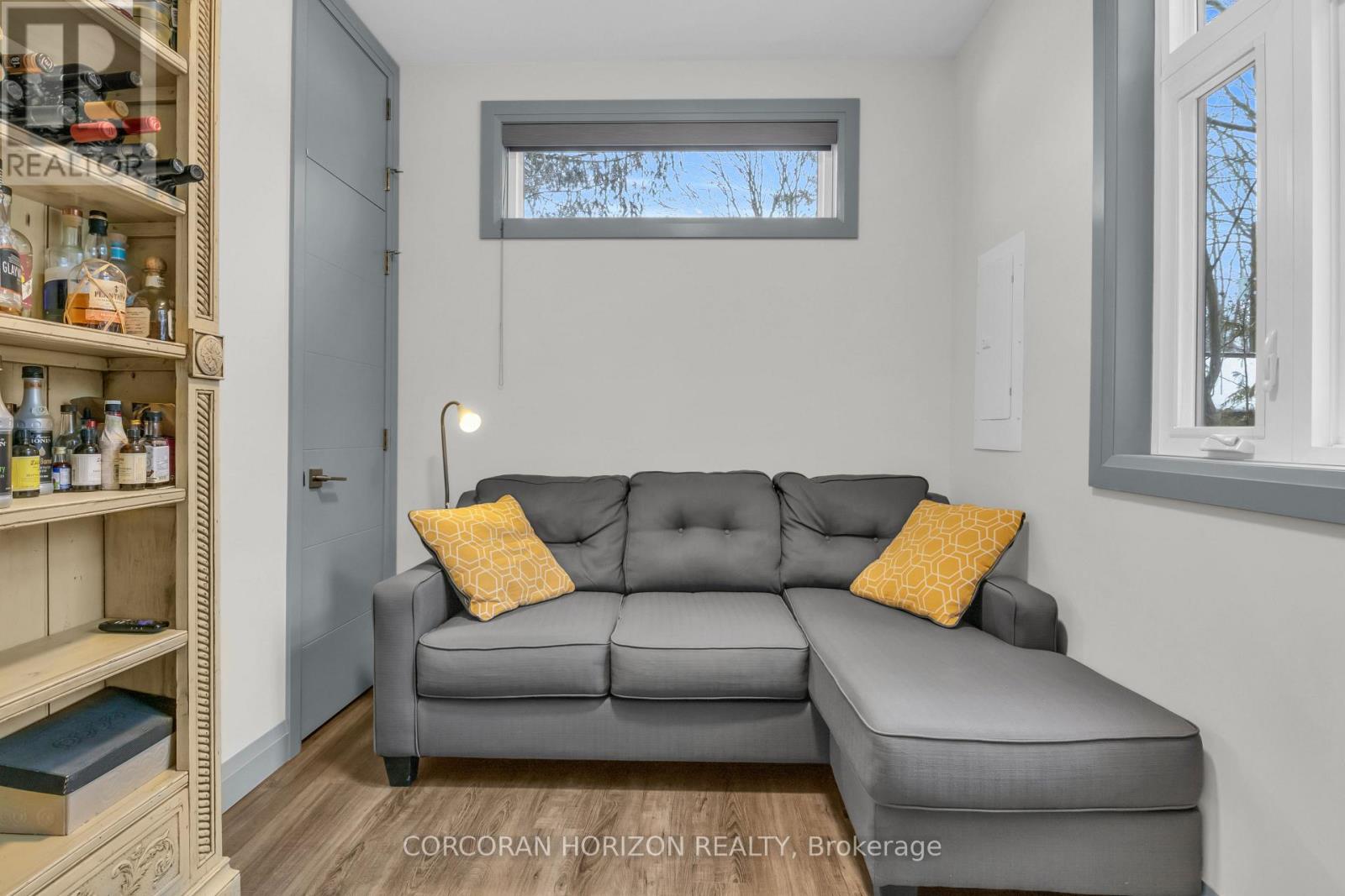 A living room with a grey couch and a wooden shelf.