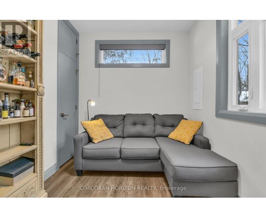 A living room with a grey couch and a wooden shelf.