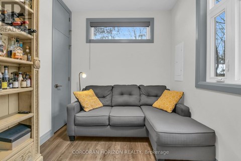 A living room with a grey couch and a wooden shelf.