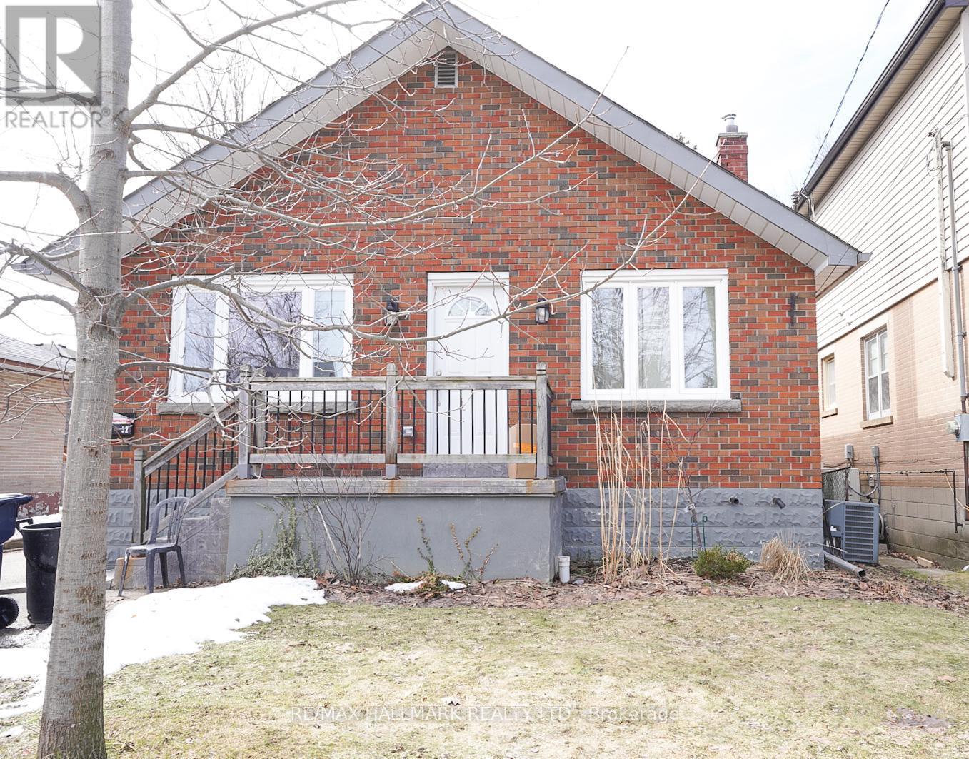 A small red brick house with a white window and a metal railing on the balcony.