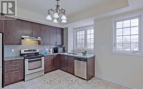 A kitchen with dark wood cabinets and stainless steel appliances is on the market.