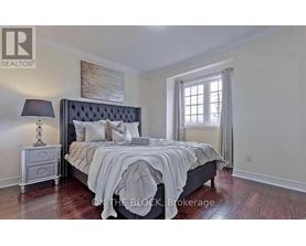 A bedroom with a large bed, a nightstand with a lamp, and a window with curtains.