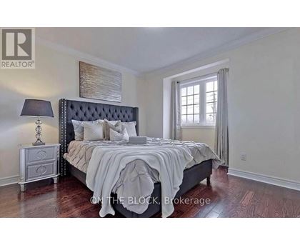 A bedroom with a large bed, a nightstand with a lamp, and a window with curtains.