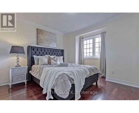 A bedroom with a large bed, a nightstand with a lamp, and a window with curtains.