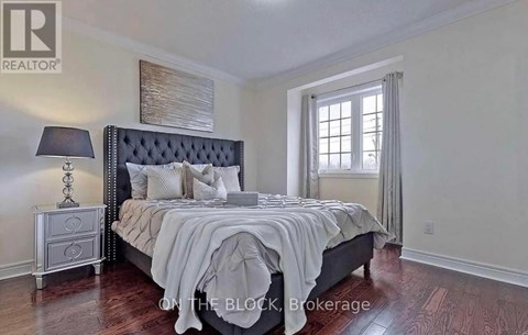 A bedroom with a large bed, a nightstand with a lamp, and a window with curtains.