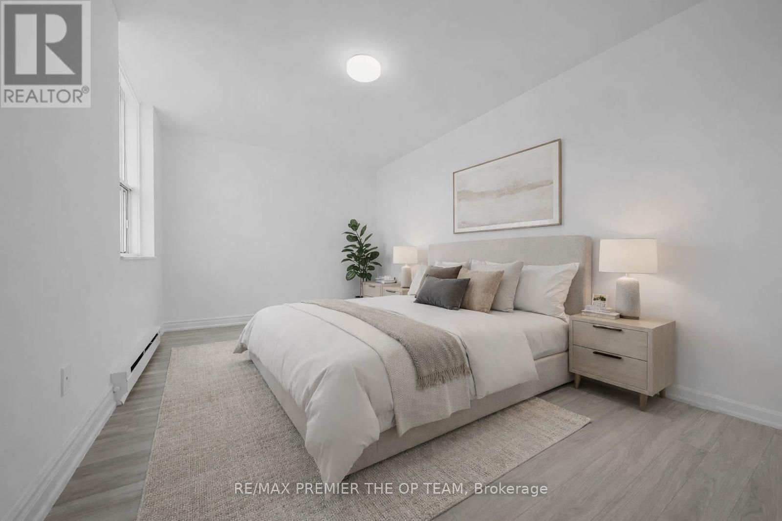 A bedroom with a large bed, nightstand, and lamp.