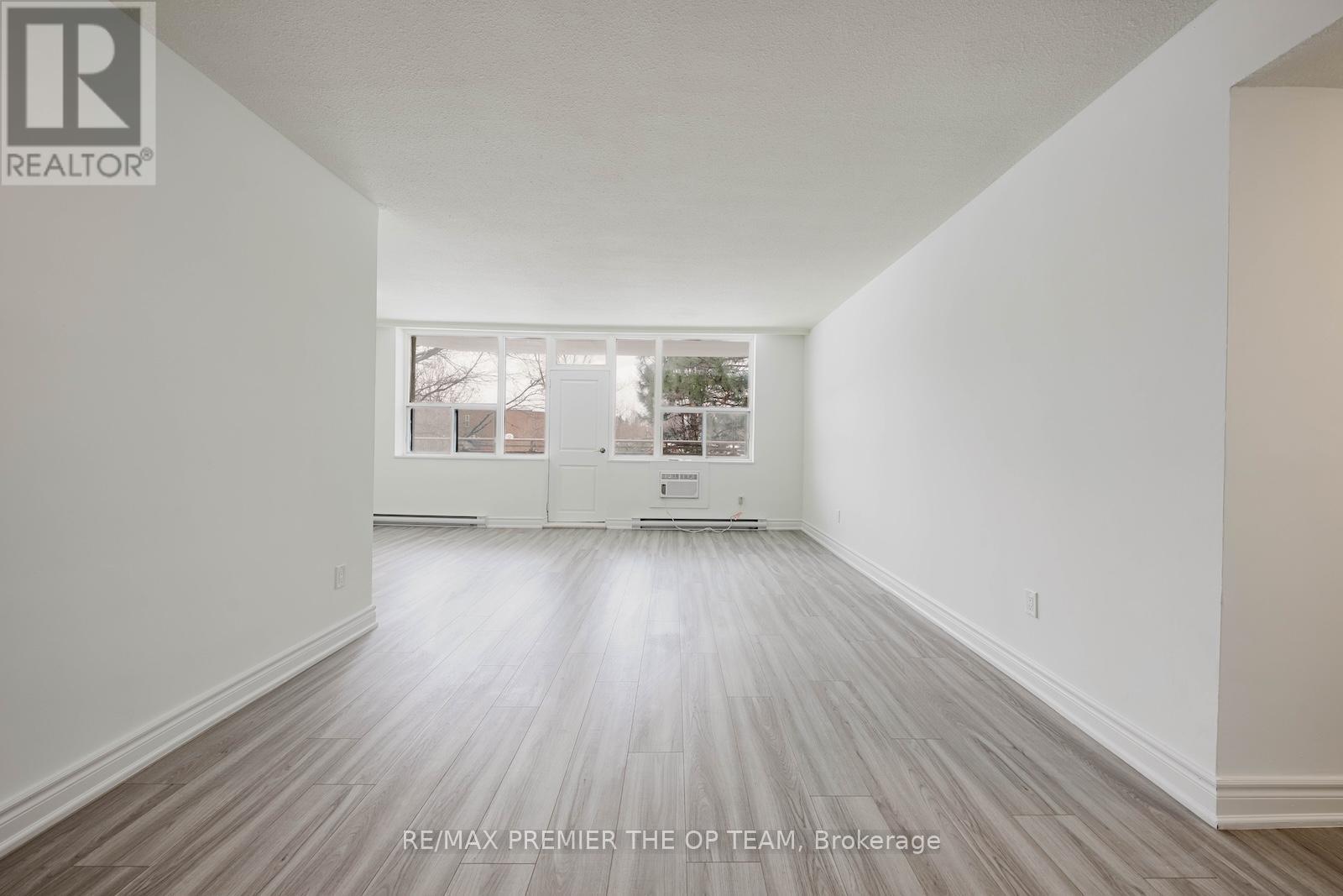 A spacious room with wooden flooring and white walls.