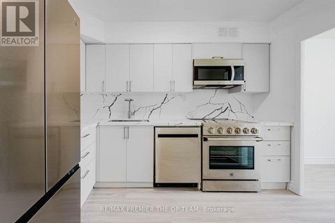 A modern kitchen with white cabinets and a marble backsplash.