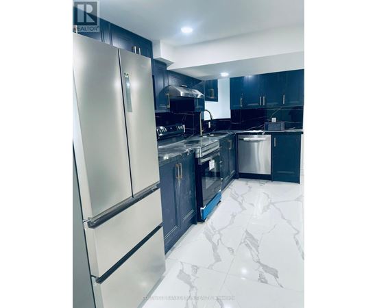 A modern kitchen with a white fridge and black cabinets.
