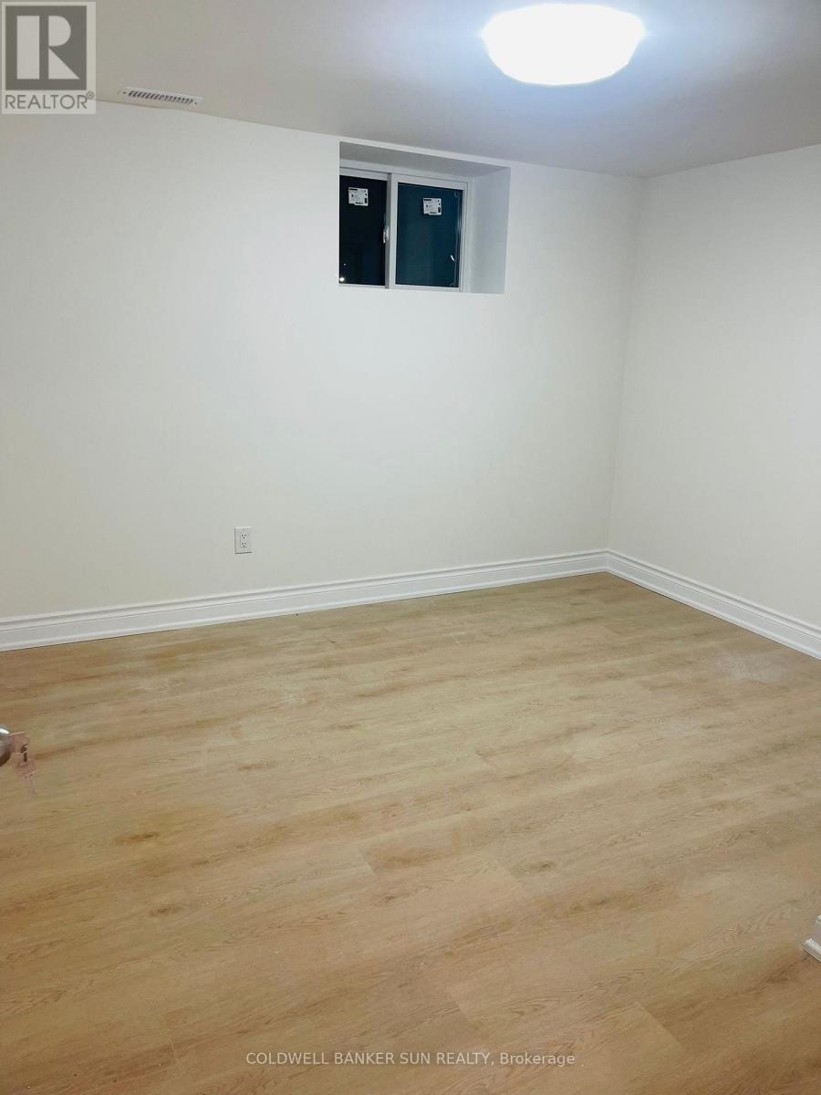 A room with a wooden floor and a white wall with a small window.