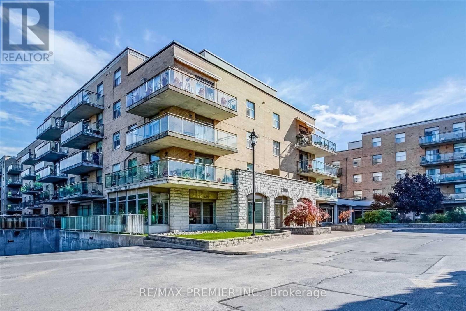 A multi-story apartment building with balconies and a parking lot in front.