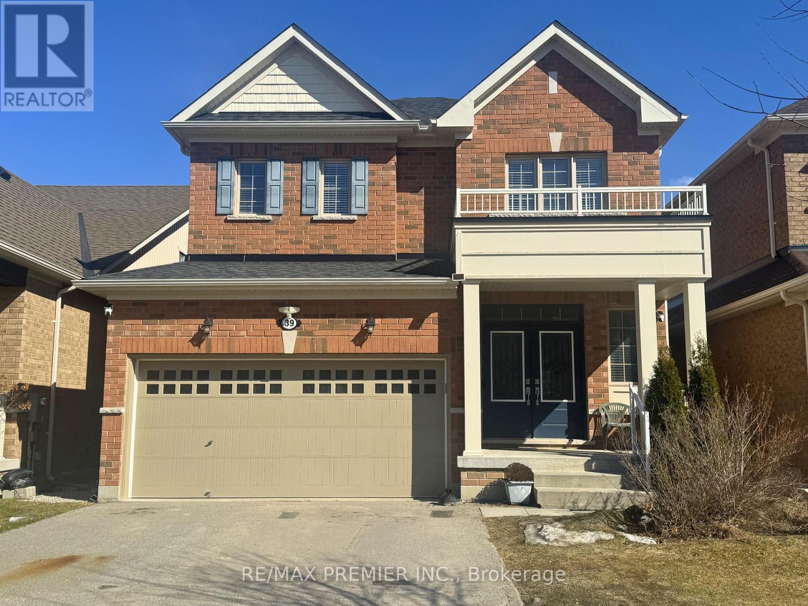 A two-story brick house with a garage and a balcony on the upper floor.