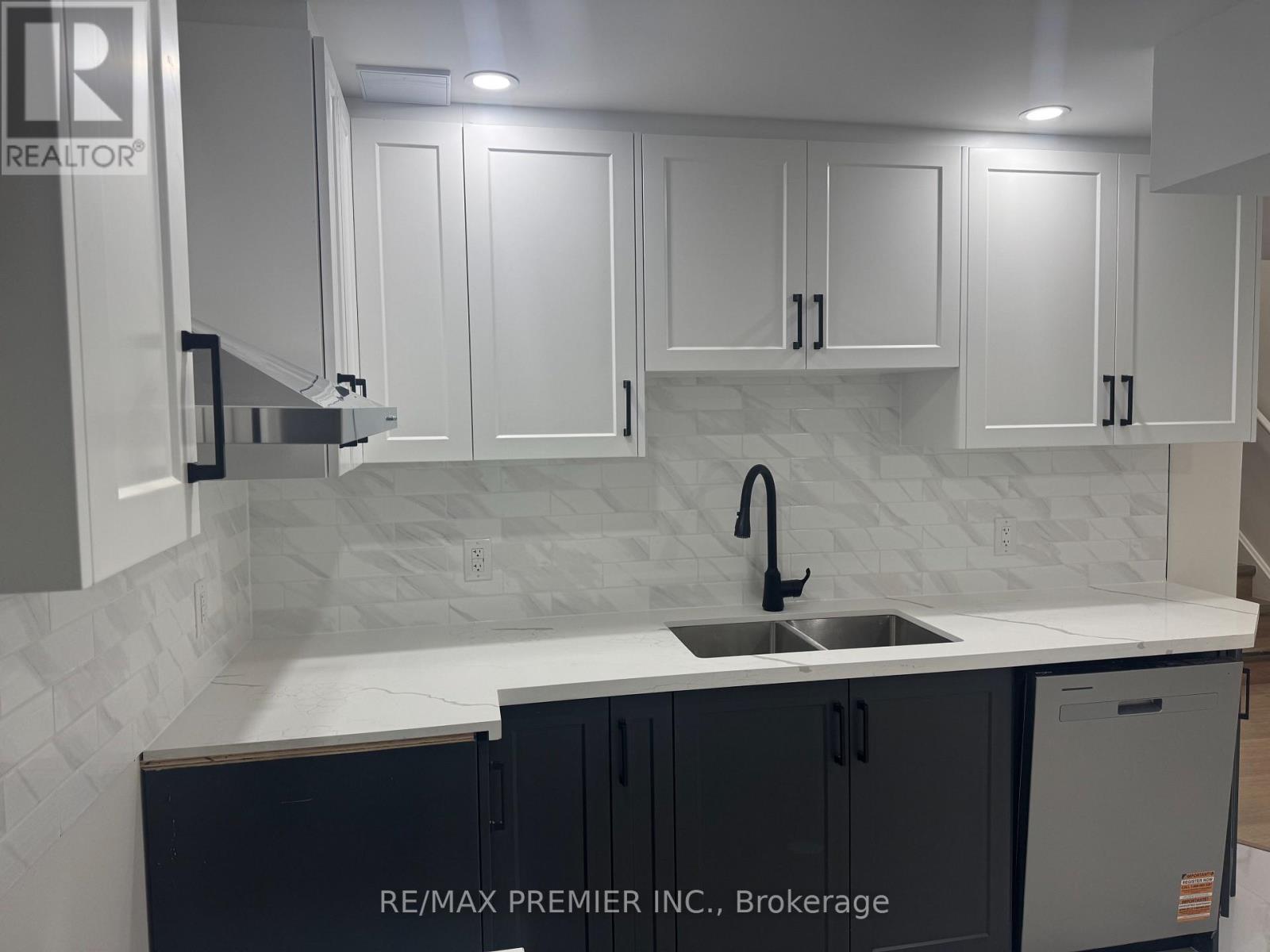 A kitchen with white cabinets and a marble backsplash.